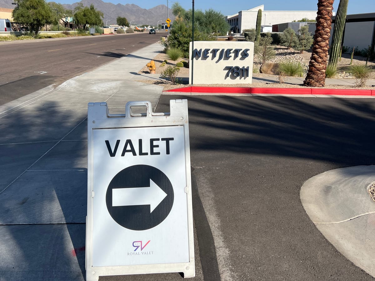 A Royal Valet directional sign at the NetJets entrance, desert landscaping and mountains behind