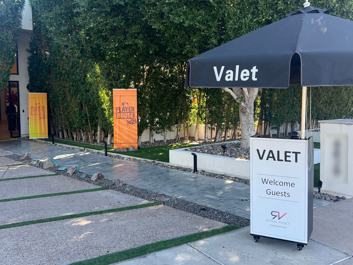 A Royal Valet “Welcome Guests” podium and umbrella at the entrance to a private event, Player House banners behind