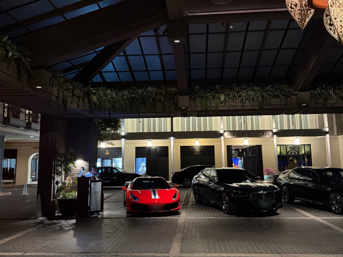 Luxury cars staged under a lit hotel porte-cochère at night