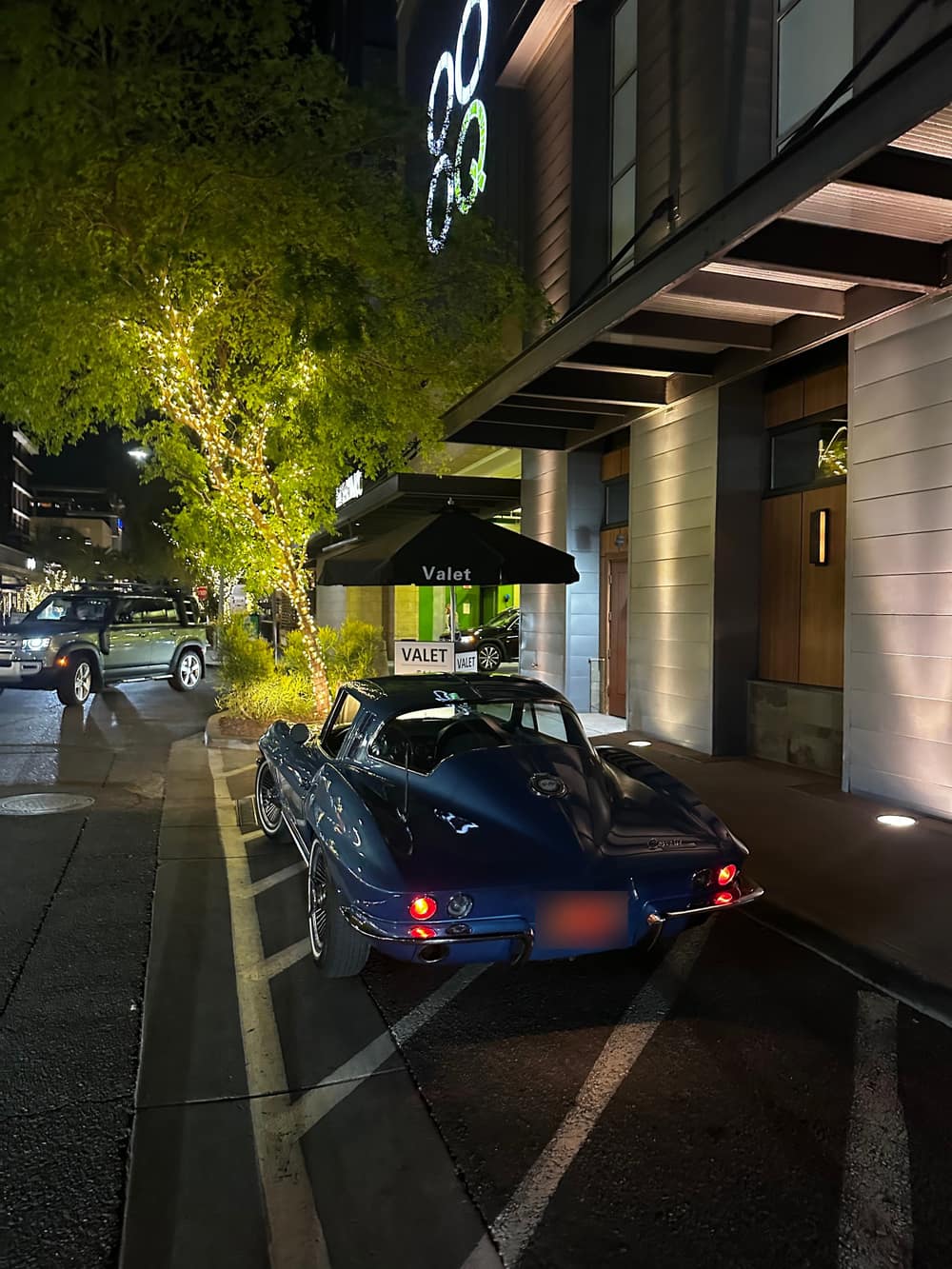 A classic blue Corvette Sting Ray at a Royal Valet stand at night
